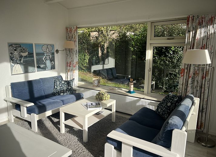 Gezellige zithoek in vakantiehuis ZE1678, Oostkapelle, Walcheren, met kunst aan de muur en uitzicht op de tuin in Zeeland.