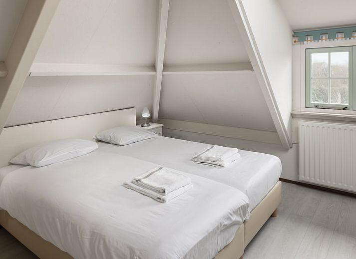 Gemuetliches Wohnzimmer des M8 Luxe Bungalows in Domburg, Walcheren, Zeeland mit bequemer Sitzecke und Strandkunst an der Wand.