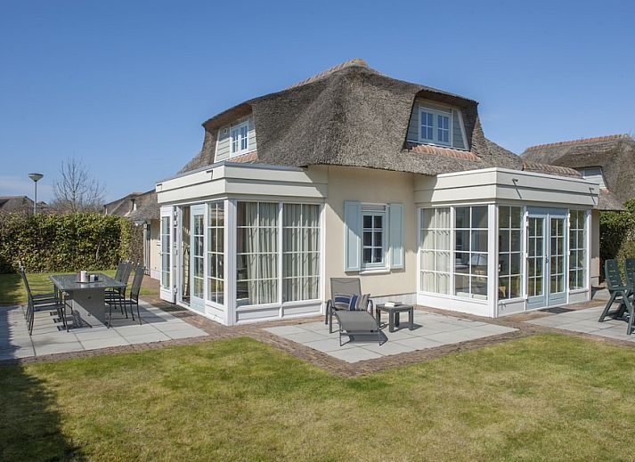 Gemuetliches Wohnzimmer des M8 Luxe Bungalows in Domburg, Walcheren, Zeeland mit bequemer Sitzecke und Strandkunst an der Wand.