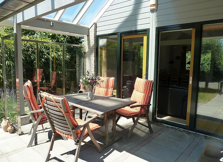 Veranda von VZ1123 Ferienhaus in Vlissingen, Walcheren, Zeeland mit Gartenmoebeln und gruener Umgebung.