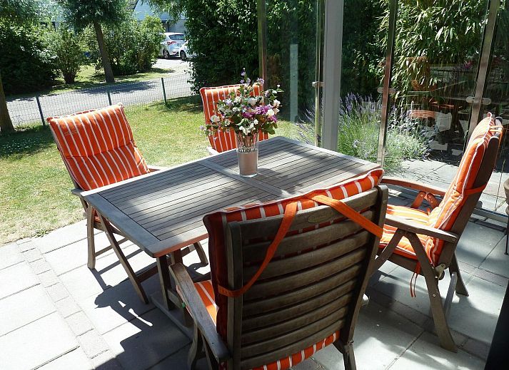 Veranda von VZ1123 Ferienhaus in Vlissingen, Walcheren, Zeeland mit Gartenmoebeln und gruener Umgebung.