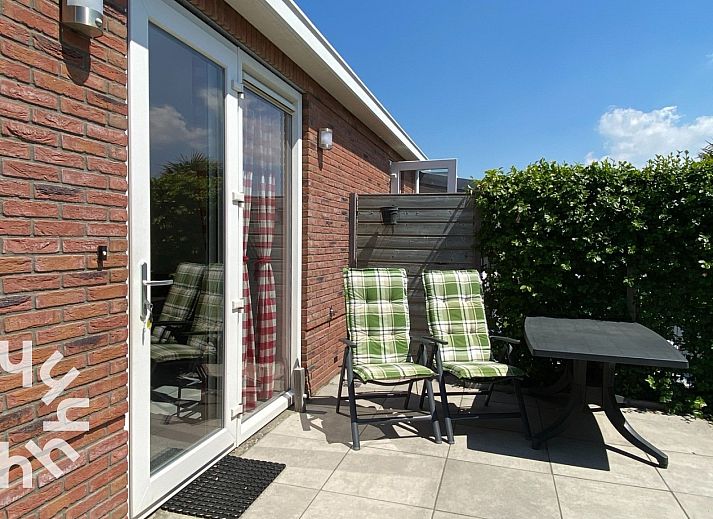 Terrasse des Ferienhauses ZE1135 in Zoutelande, Walcheren, mit bequemen Stuehlen und Tisch fuer Mahlzeiten im Freien.