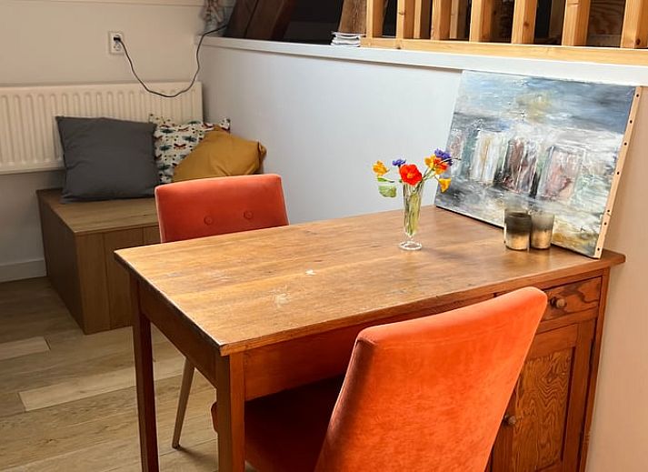 Charmant terras bij Vakantiehuis in Arnemuiden, Walcheren, Zeeland met groene klimop en houten stoelen.