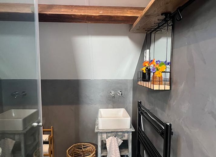 Lichte binnenruimte van Vakantiehuis in Arnemuiden, Walcheren, Zeeland met houten trap en zitgedeelte.