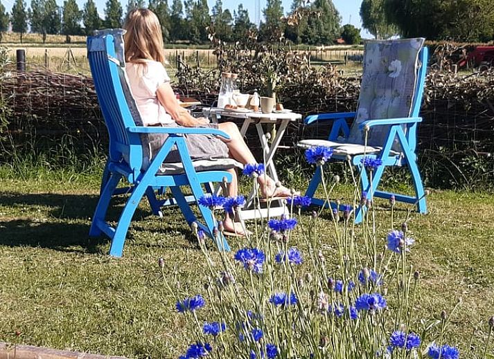 Lichte binnenruimte van Vakantiehuis in Arnemuiden, Walcheren, Zeeland met houten trap en zitgedeelte.