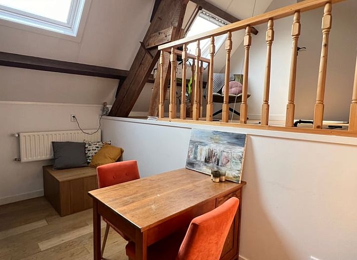 Lichte binnenruimte van Vakantiehuis in Arnemuiden, Walcheren, Zeeland met houten trap en zitgedeelte.