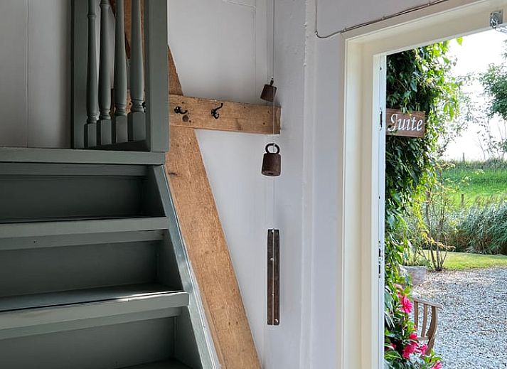 Lichte binnenruimte van Vakantiehuis in Arnemuiden, Walcheren, Zeeland met houten trap en zitgedeelte.