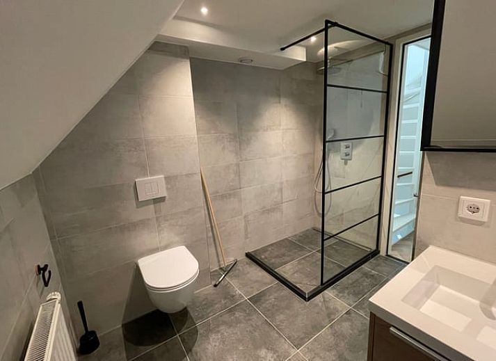 Gemuetliches Wohnzimmer des Ferienhauses in Veere, Walcheren, Zeeland mit bequemem Sofa und stilvollen Pflanzen fuer einen entspannten Aufenthalt.