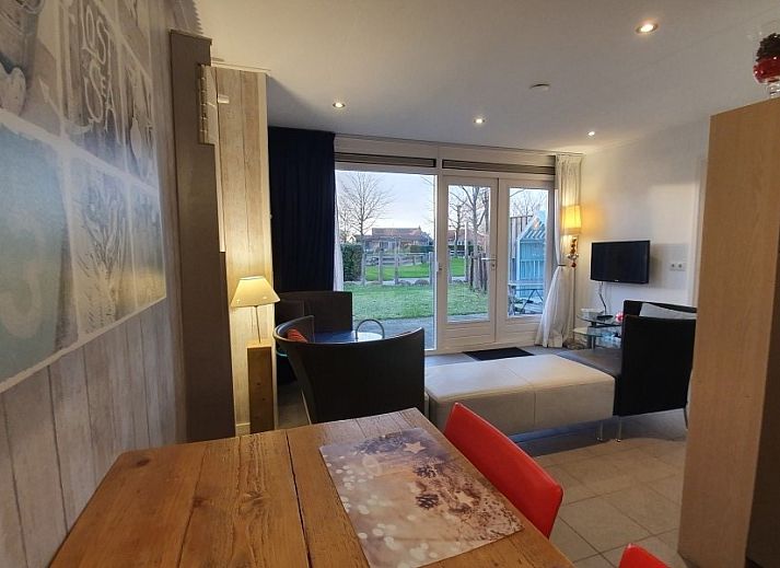 Gemuetliche Terrasse am Ferienhaus THE SUN IN STEE ON ZEE in Serooskerke, Walcheren, mit bequemen Sitzgelegenheiten und Blumen.