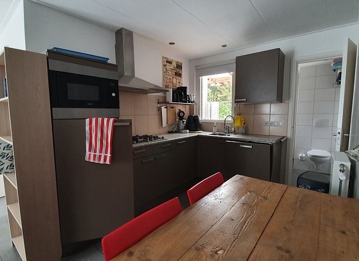 Gemuetliche Terrasse am Ferienhaus THE SUN IN STEE ON ZEE in Serooskerke, Walcheren, mit bequemen Sitzgelegenheiten und Blumen.