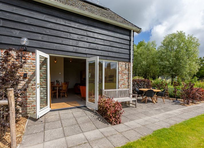 Ruime tuin van Vakantiehuis De kleine Pionier in Grijpskerke, Walcheren, Zeeland met ligstoelen en groene omgeving.