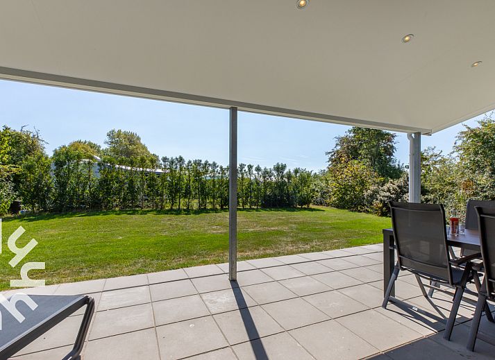 Zonnig terras van vakantiehuis ZE1470 in Grijpskerke, Walcheren, met ligstoelen en tijdschrift.