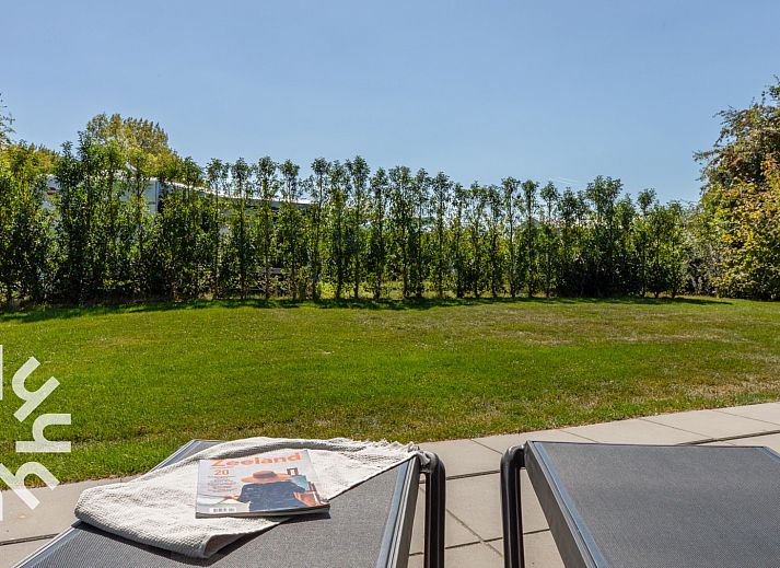 Zonnig terras van vakantiehuis ZE1470 in Grijpskerke, Walcheren, met ligstoelen en tijdschrift.