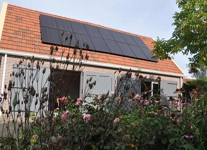 Glazen schuifdeuren openen naar een lichte binnenruimte in Vakantiehuis in Nieuw- en Sint Joosland, Walcheren, Zeeland.