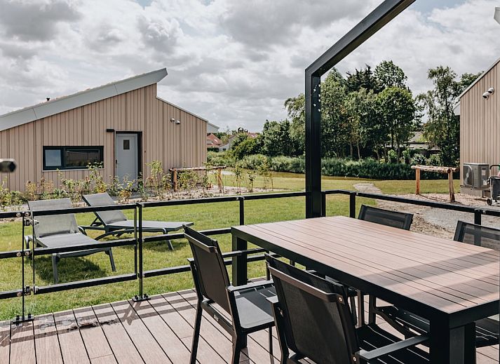 Moderne woonkamer van bungalow Zeeaster 4 in Breskens, Zeeuws-Vlaanderen, met lichte inrichting en uitzicht op de tuin.