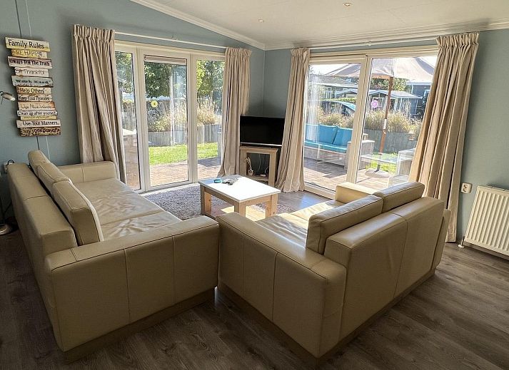 Terrasse des VZ808 Ferienhauses in Breskens mit Holzmoebeln und Sonnenschirm, Zeeland.