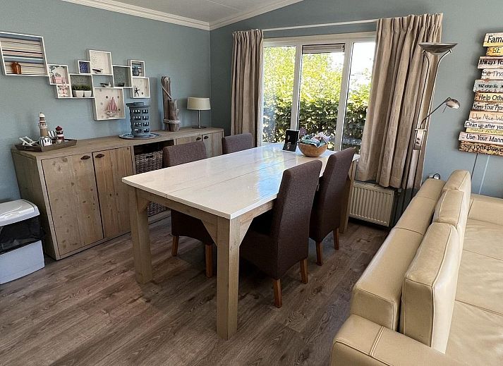 Terrasse des VZ808 Ferienhauses in Breskens mit Holzmoebeln und Sonnenschirm, Zeeland.