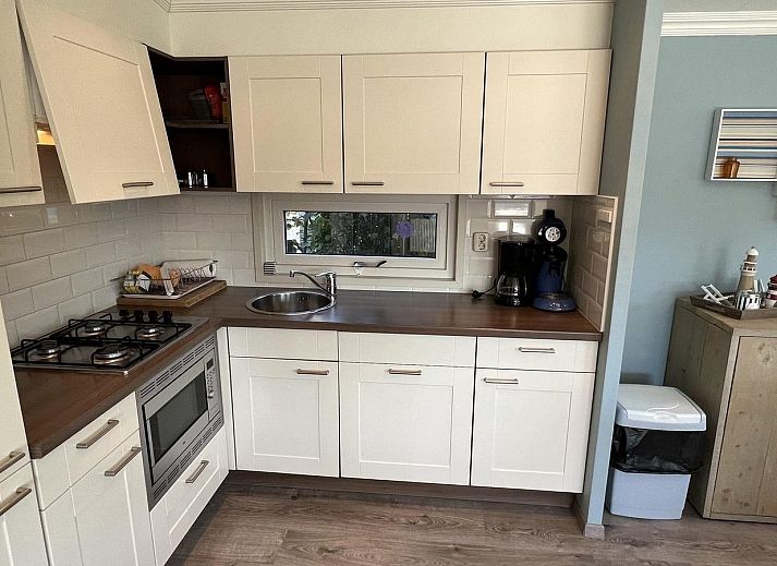 Terrasse des VZ808 Ferienhauses in Breskens mit Holzmoebeln und Sonnenschirm, Zeeland.