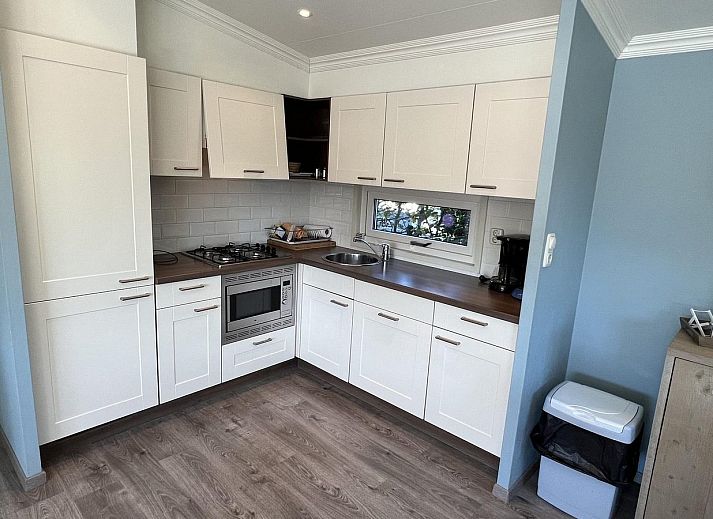 Terrasse des VZ808 Ferienhauses in Breskens mit Holzmoebeln und Sonnenschirm, Zeeland.