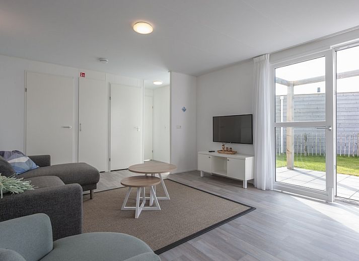 Veranda of L4K Comfort vacation home in Nieuwvliet-Bad, Zeeuws-Vlaanderen, overlooking green surroundings and blue sky.