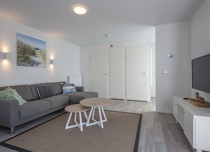 Modern living room of L4K Comfort vacation home in Nieuwvliet-Bad, Zeeuws-Vlaanderen, with bright interior and access to sunny terrace.