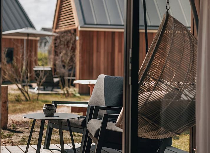 Entspannen Sie sich auf der stilvollen Veranda von Tiny House 4 in Nieuwvliet-Bad, Zeeuws-Vlaanderen, einem charmanten Ferienhaus in Zeeland.
