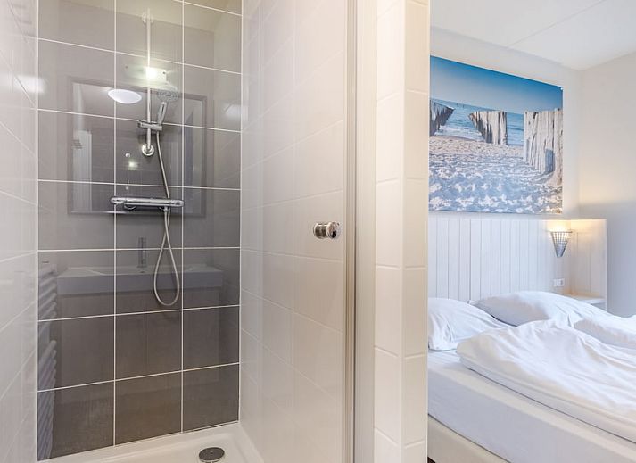 Sfeervolle slaapkamer in Villa 6B, een vakantiehuis in Cadzand-bad, Zeeuws-Vlaanderen, met comfortabele bedden en warme verlichting.