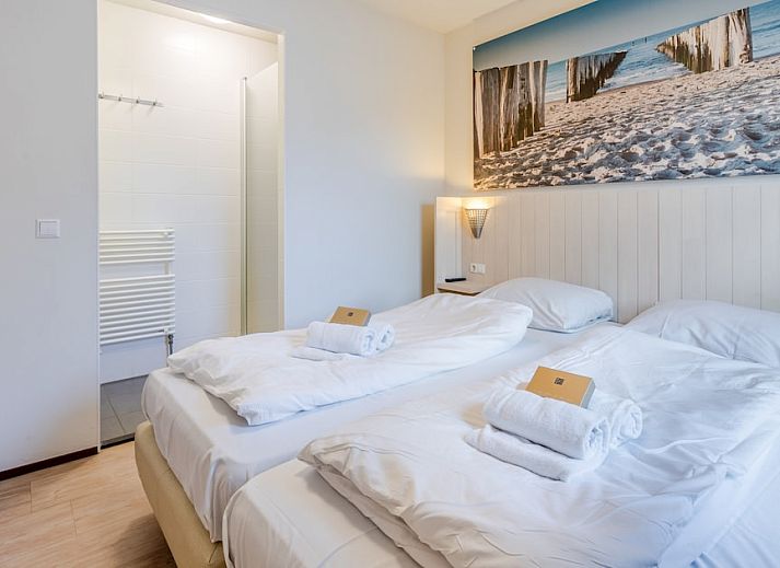 Sfeervolle slaapkamer in Villa 6B, een vakantiehuis in Cadzand-bad, Zeeuws-Vlaanderen, met comfortabele bedden en warme verlichting.