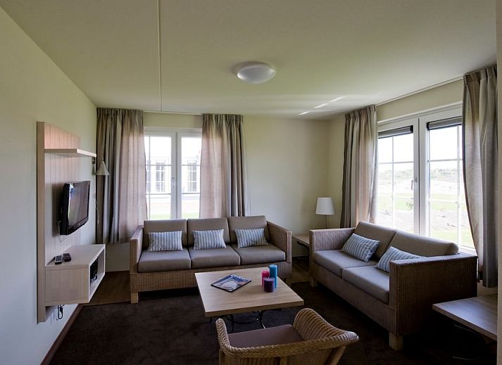 Gezellige woonkamer in Villa 6A, een vakantiehuis in Cadzand-bad, Zeeuws-Vlaanderen, met comfortabele banken en uitzicht op de natuur.