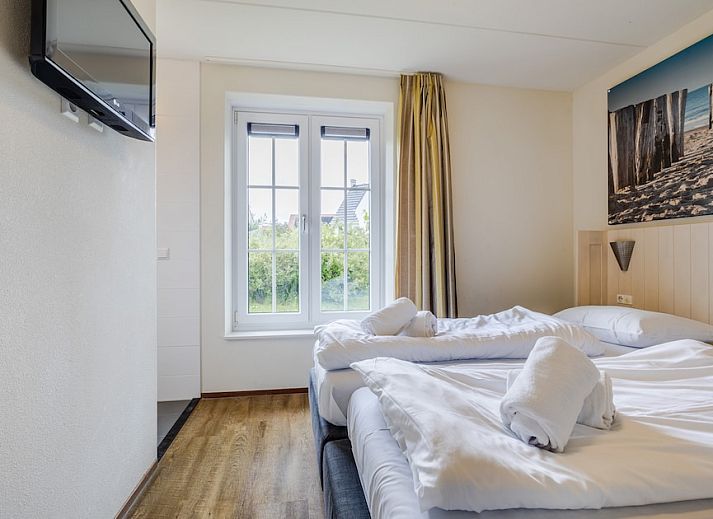 Sfeervolle slaapkamer in Villa 9A, vakantiehuis in Cadzand-bad, Zeeuws-Vlaanderen, Zeeland, met twee comfortabele bedden en natuurlijk licht.