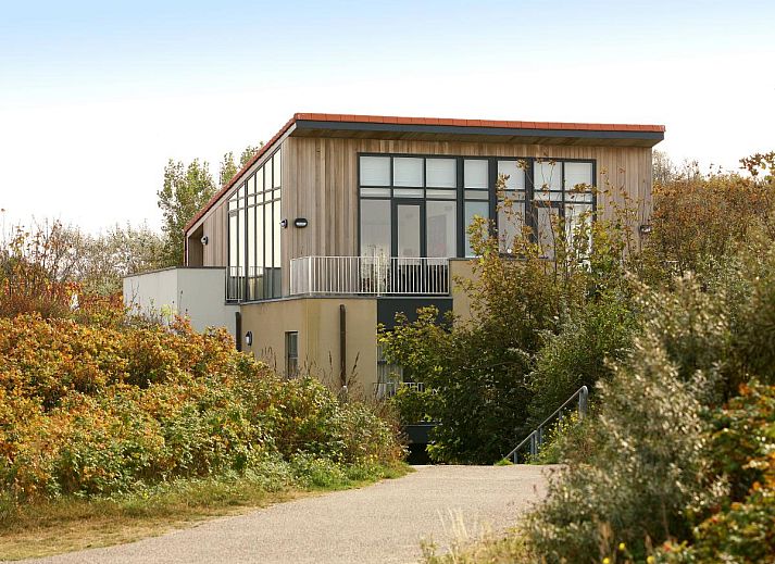 Ruime woonkamer in vakantiehuis Maanvis in Cadzand met grote ramen en veel lichtinval.