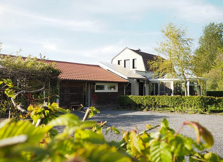 Vakantiehuis in Sluis biedt een rustieke ervaring in Zeeuws-Vlaanderen, Zeeland, omgeven door groene natuur en een zonnig terras.