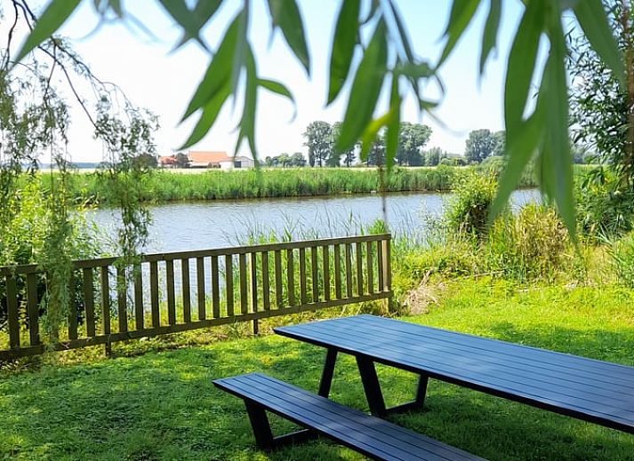 Vakantiehuis in Sluis, Zeeuws-Vlaanderen, omgeven door groene natuur en een uitgestrekt gazon, ideaal voor een ontspannen verblijf.