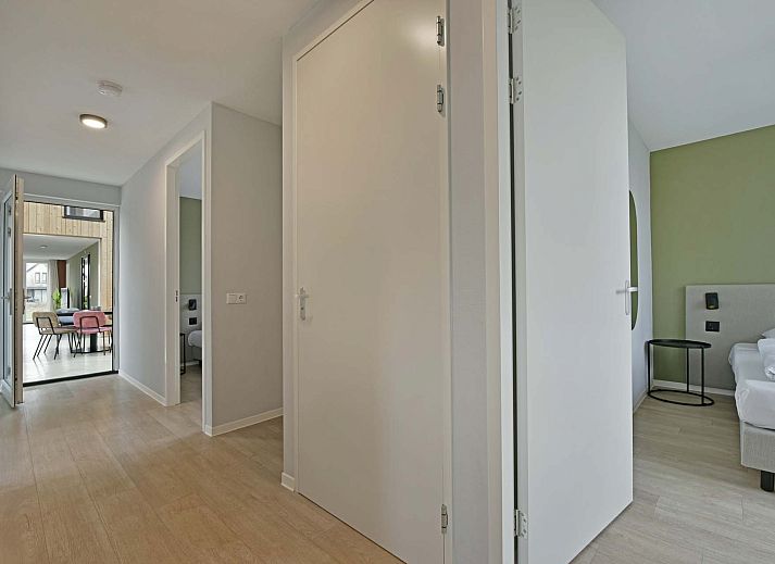 Helles Wohnzimmer eines freistehenden Hauses in Nieuwvliet, Zeeuws-Vlaanderen, mit grozgiger Sitzbank und Blick auf die grne Umgebung.