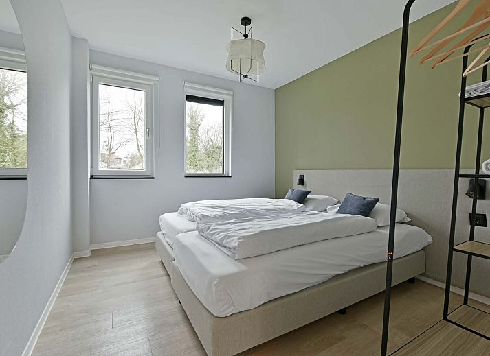 Helles Wohnzimmer eines freistehenden Hauses in Nieuwvliet, Zeeuws-Vlaanderen, mit grozgiger Sitzbank und Blick auf die grne Umgebung.