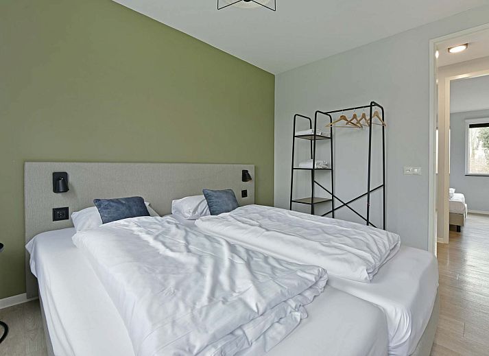 Helles Wohnzimmer eines freistehenden Hauses in Nieuwvliet, Zeeuws-Vlaanderen, mit grozgiger Sitzbank und Blick auf die grne Umgebung.