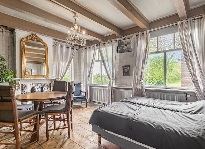 Sfeervolle slaapkamer in Vakantiehuis Groepswoning De Appelgaard, Zaamslag, met antieke muurschilderingen en houten vloer.