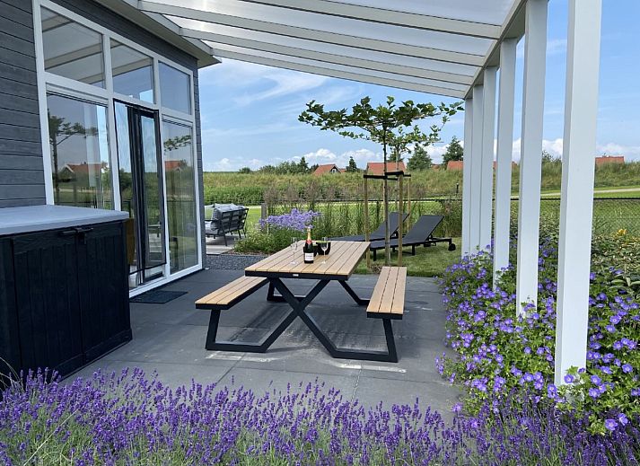Dining room in Holiday home Ruisweg 83, Wemeldinge, with wooden table and view of outside.