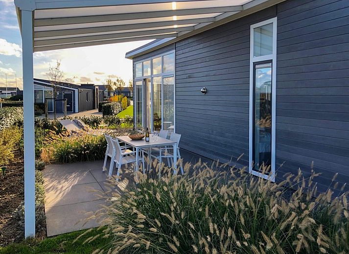 Vakantiehuis Waterresort Oosterschelde huisnr. 85 in Wemeldinge, omgeven door groene heggen en bloeiende bomen.