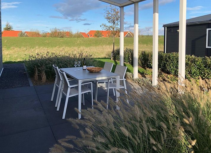 Terras met eettafel bij Vakantiehuis Waterresort Oosterschelde huisnr. 85 in Wemeldinge, Zuid-Beveland, omringd door natuur.