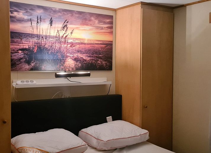 Seitenansicht des 4-Staemme-Chalets auf dem Campingplatz Ardoer, Zuid-Beveland, umgeben von gruener Natur