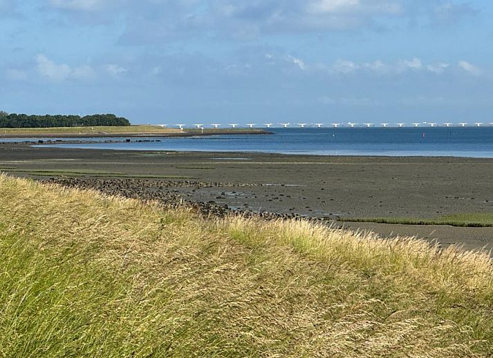 Rustige omgeving van vakantiehuis ZE1365 in Kattendijke, met uitzicht op een groene weide en kerktoren.