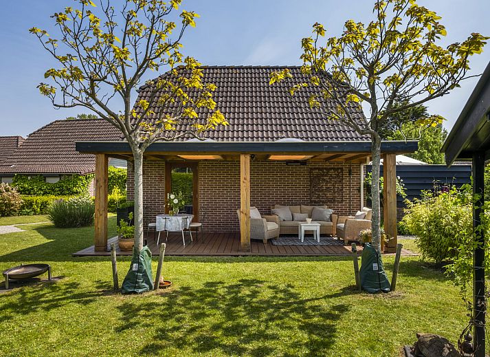 Geniessen Sie den sonnigen Garten des Ferienhauses Haus Anni in Hansweert, Zuid-Beveland, mit gemuetlicher Sitzecke und Sonnenschirm.