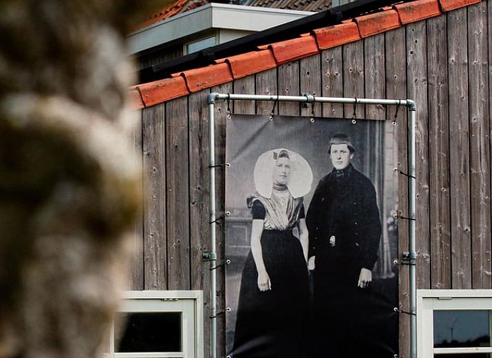 Binnenruimte van Vakantiehuisje in Lewedorp, Zuid-Beveland, met uitzicht op de natuur. Gezellige inrichting met bloemen en kaart aan de muur.