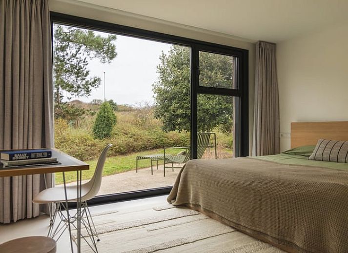 Gemuetlicher Essbereich im Ferienhaus in Ouddorp mit Blick auf den gruenen Garten, gelegen in Ouddorp, Goeree-Overflakkee, Suedholland.