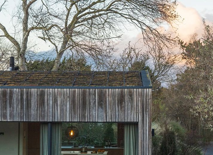 Ferienhaus in Ouddorp, eine moderne Ferienunterkunft inmitten der Natur auf Goeree-Overflakkee, Suedholland, mit grossem Garten und Holzfassade.