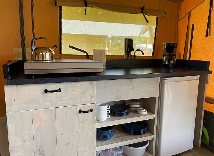 Gemuetlicher Innenbereich des Safaritent Zeeduin in Ouddorp, Goeree-Overflakkee, mit Kueche und Sitzecke in einer Glamping-Lodge.