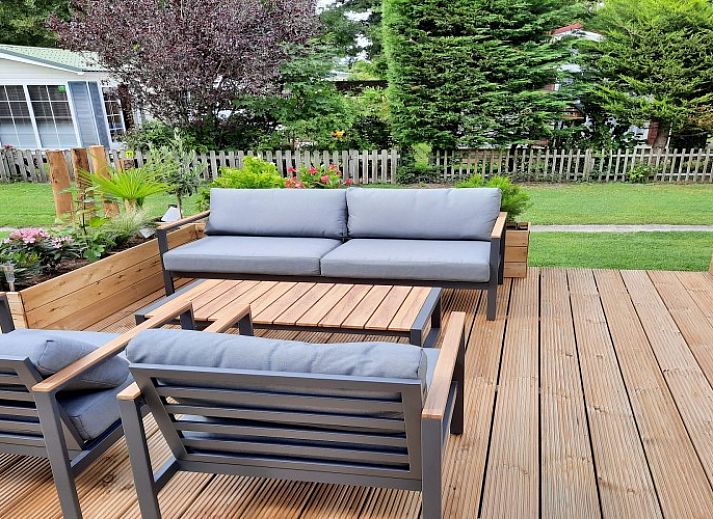 Chalet Sunrise with private beach garden in Ouddorp, Zeeland, offers a sunny terrace with comfortable deck chairs and green views.