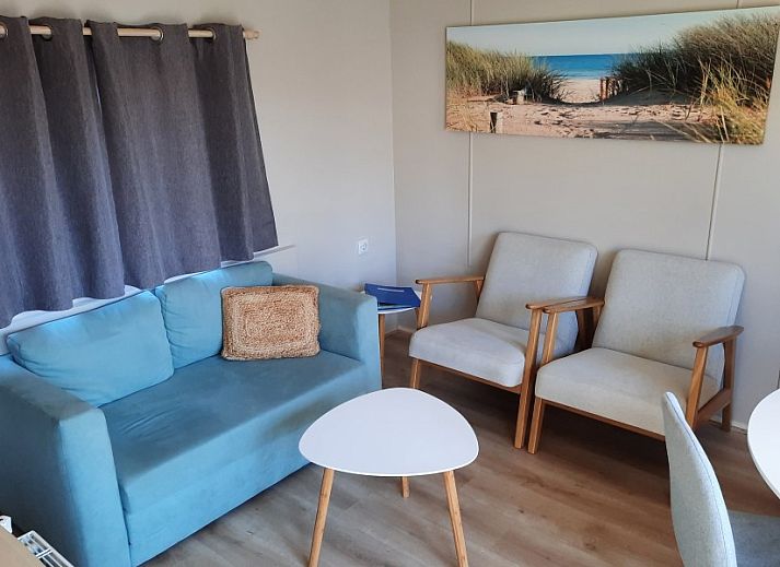 Relax in the quiet sandy garden of Chalet Sunrise in Ouddorp, Zeeland, with comfortable chairs and surrounding nature.