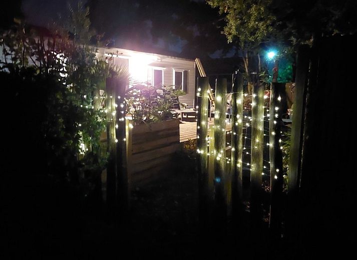 Relax in the quiet sandy garden of Chalet Sunrise in Ouddorp, Zeeland, with comfortable chairs and surrounding nature.